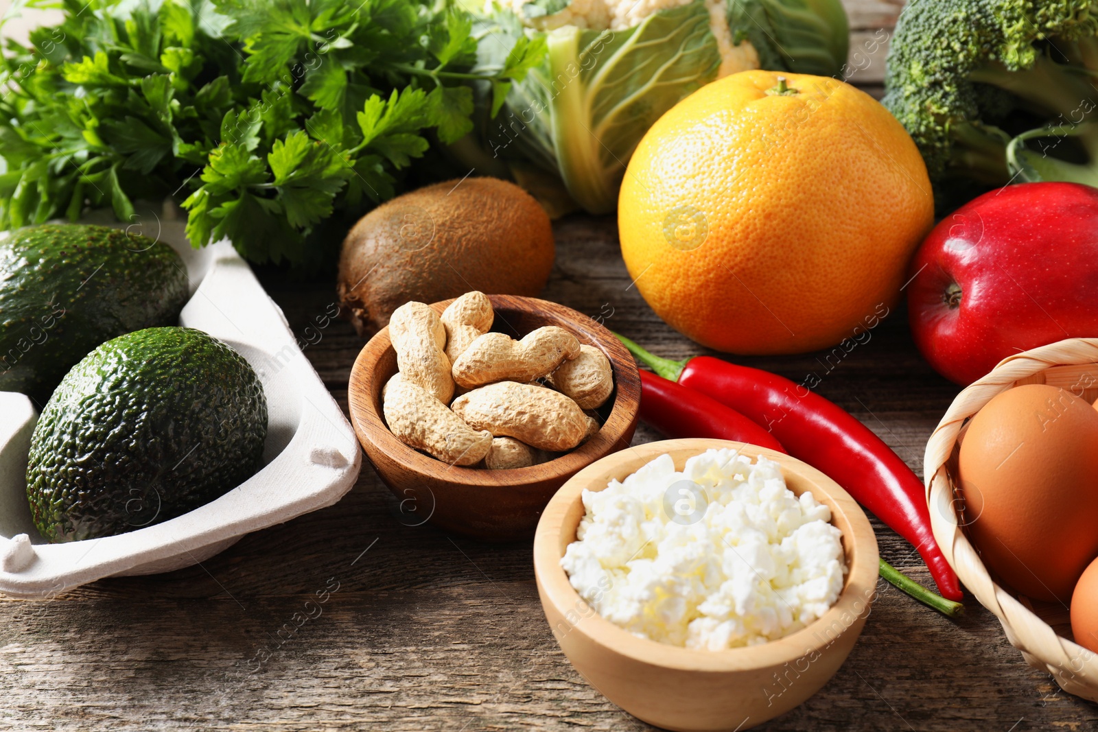 Photo of Healthy meal. Different vegetables and raw eggs on wooden table, closeup