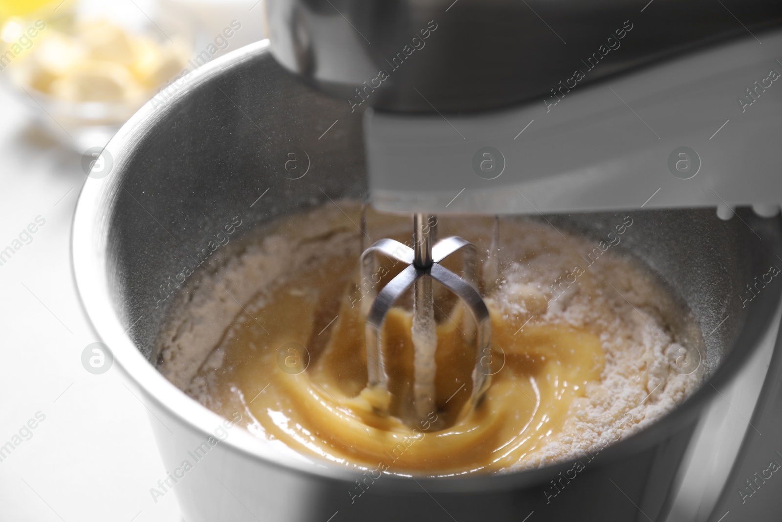 Photo of Making dough in bowl of stand mixer on white table, closeup