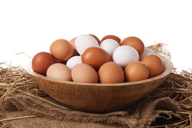 Fresh chicken eggs in bowl and dried straw on table against white background