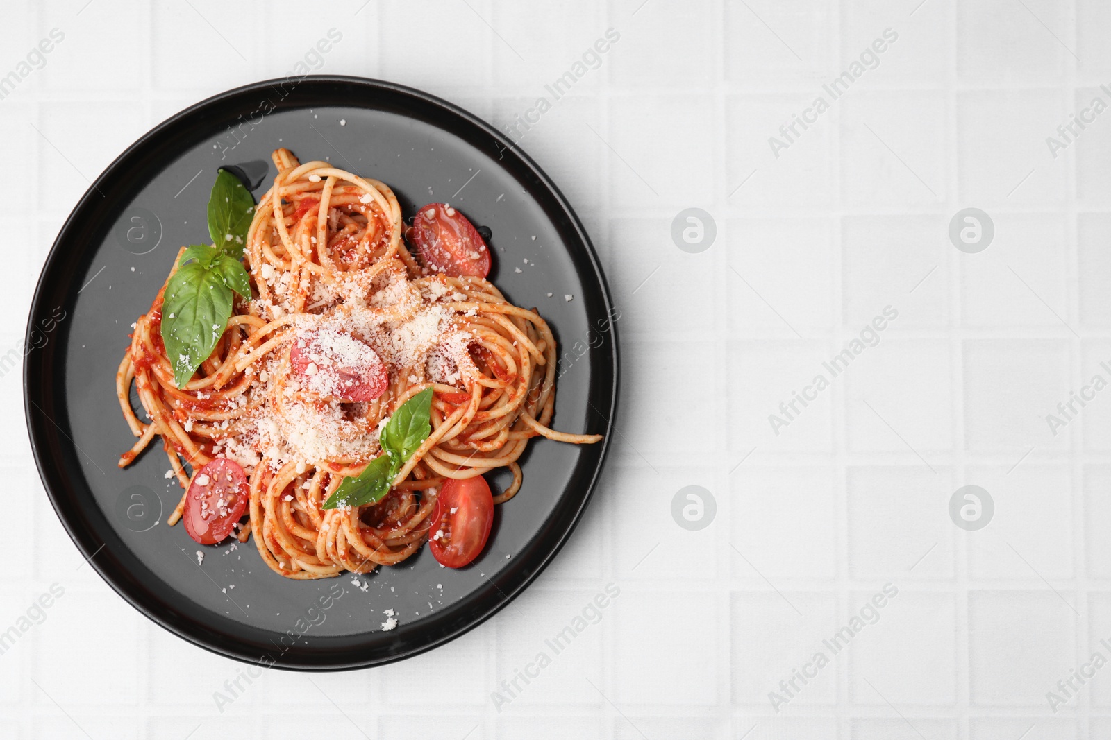 Photo of Tasty pasta with tomato sauce, cheese and basil on white tiled table, top view. Space for text