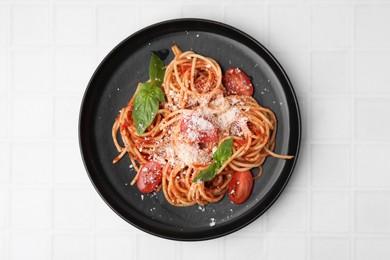 Tasty pasta with tomato sauce, cheese and basil on white tiled table, top view