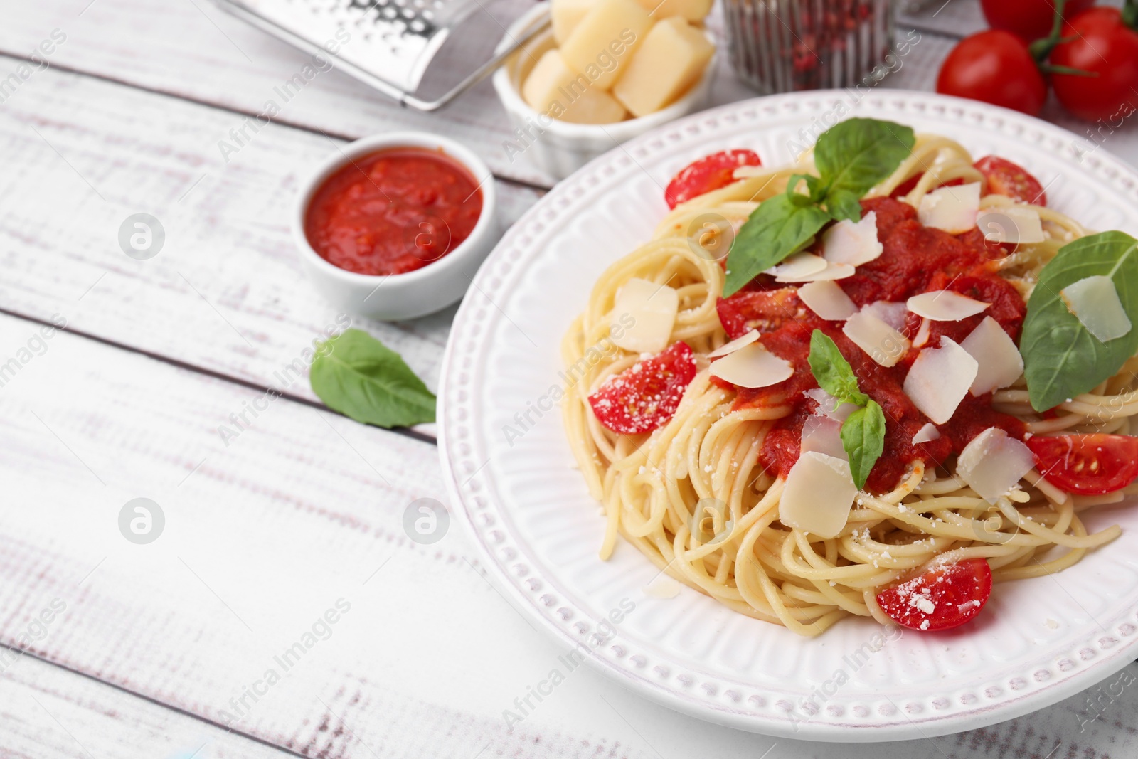 Photo of Tasty pasta with tomato sauce, cheese and basil on white wooden table, space for text