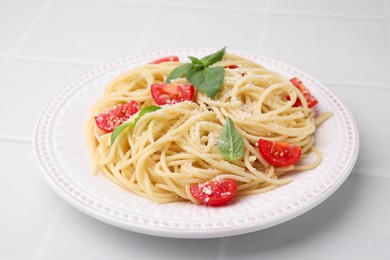 Tasty pasta with tomato, cheese and basil on white tiled table