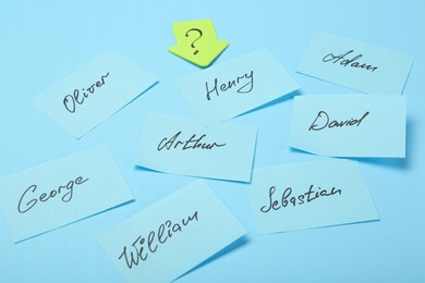 Photo of Choosing baby name. Paper stickers with different names and question mark on light blue background