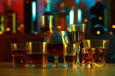 Photo of Different liqueurs in glasses on table in bar