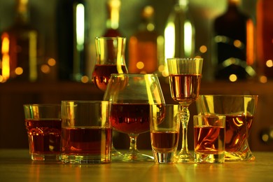 Different liqueurs in glasses on table in bar