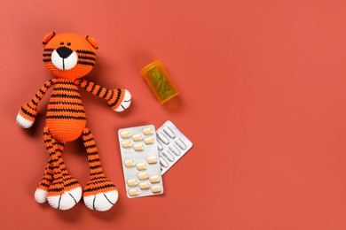 Toy tiger and pills on orange background, flat lay. Space for text