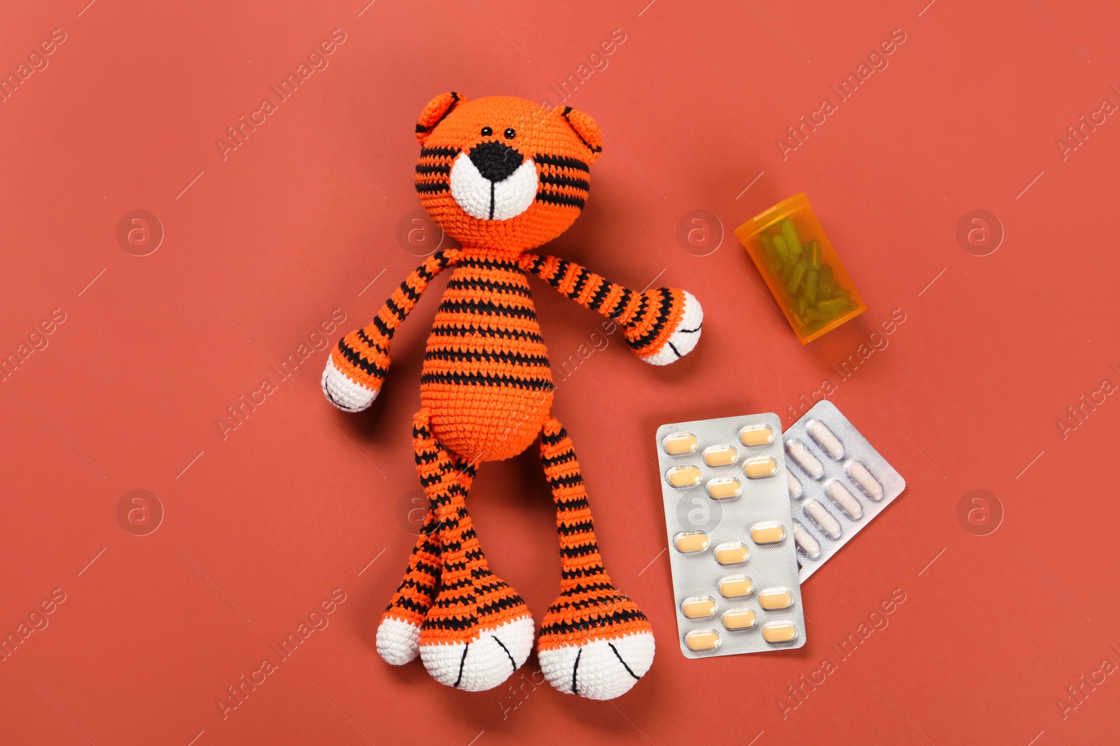 Photo of Toy tiger and pills on orange background, flat lay