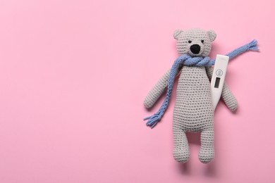 Toy bear and thermometer on pink background, top view. Space for text