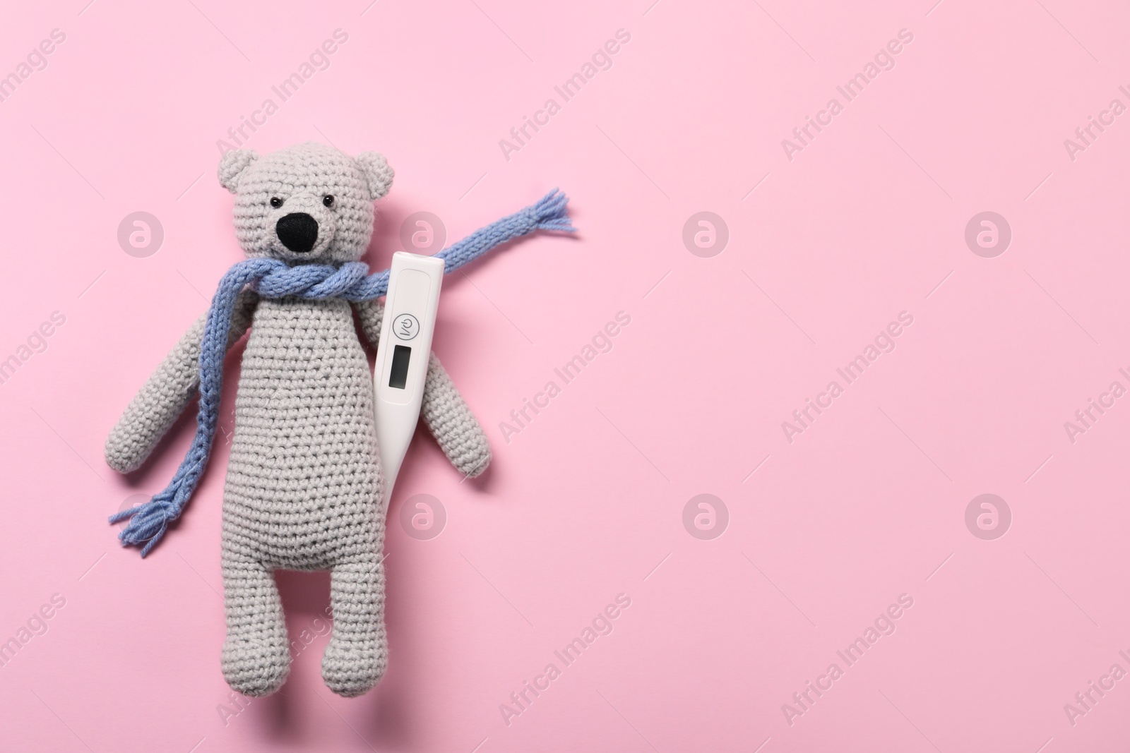 Photo of Toy bear and thermometer on pink background, top view. Space for text
