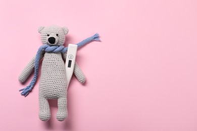 Toy bear and thermometer on pink background, top view. Space for text