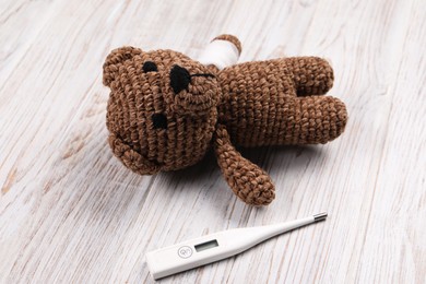 Toy bear and thermometer on wooden background