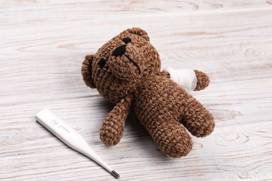 Photo of Toy bear and thermometer on wooden background