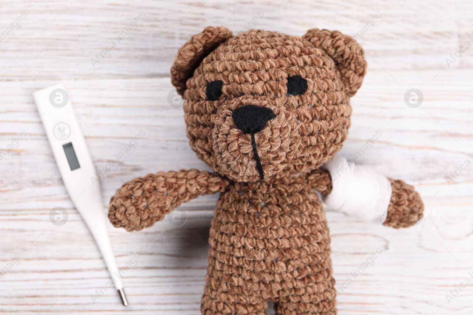 Photo of Toy bear and thermometer on wooden background, flat lay