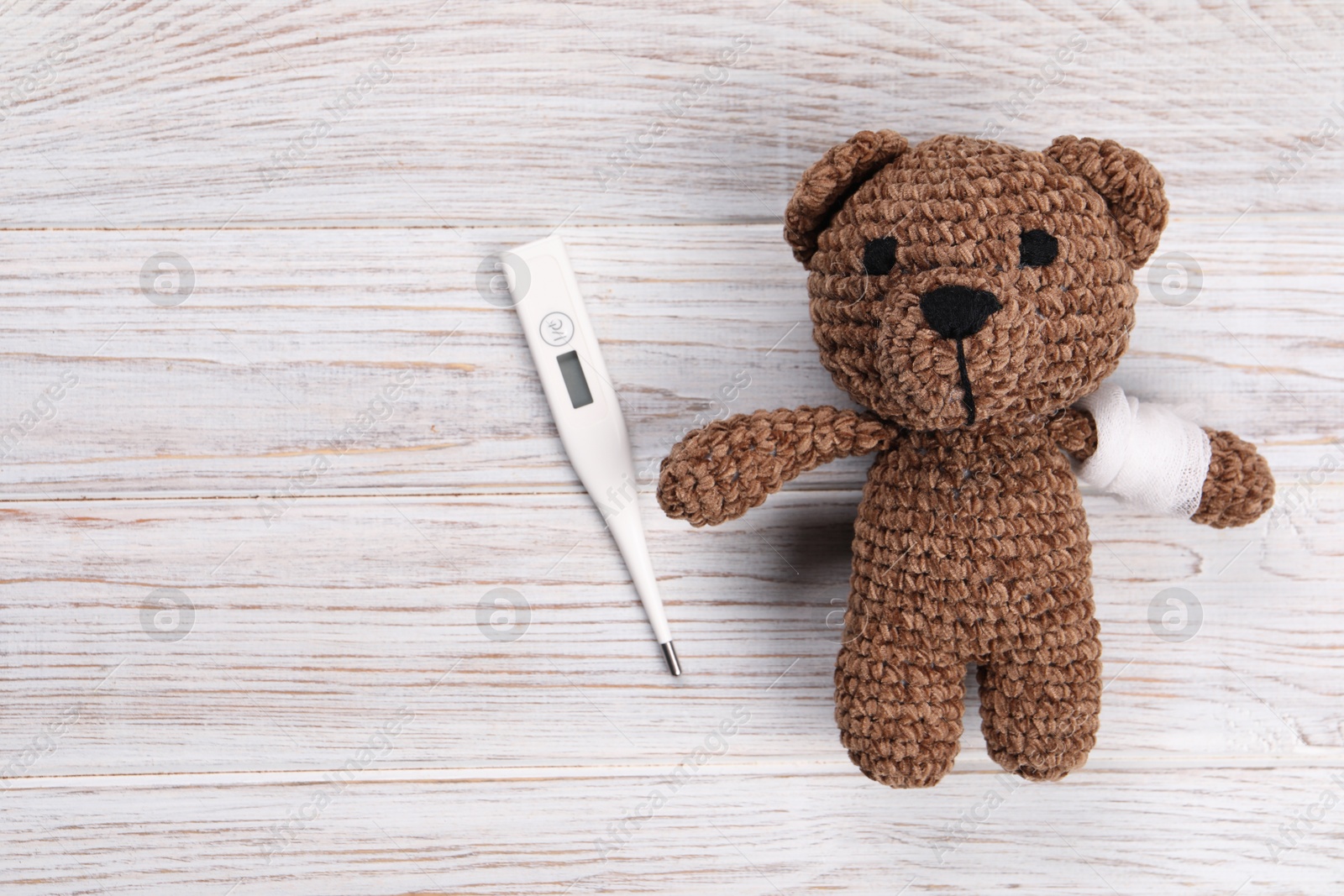 Photo of Toy bear and thermometer on wooden background, flat lay. Space for text