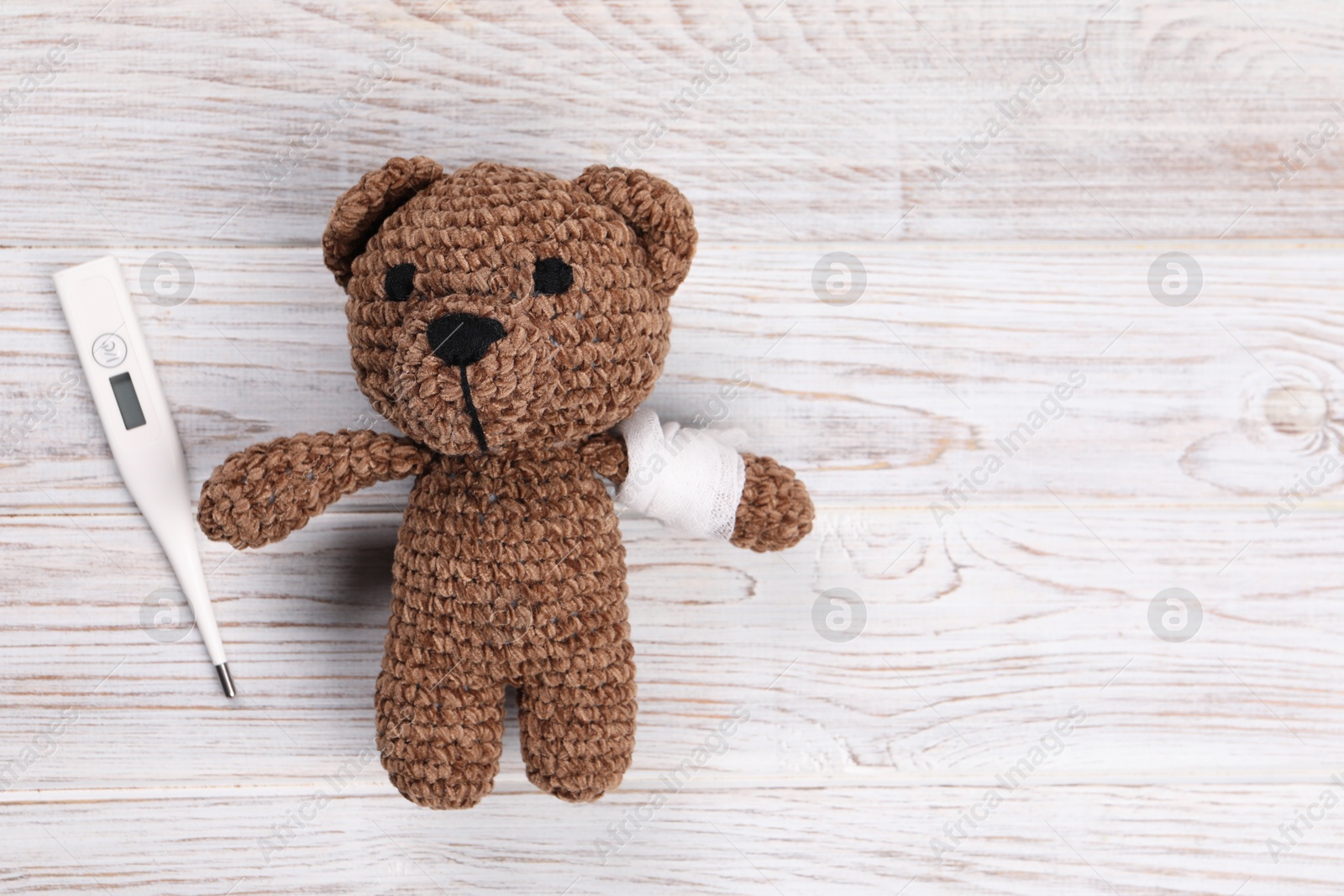 Photo of Toy bear and thermometer on wooden background, flat lay. Space for text