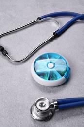 Photo of Stethoscope and pills on gray background, closeup. Medical treatment