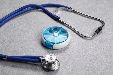 Stethoscope and pills on gray background, closeup. Medical treatment