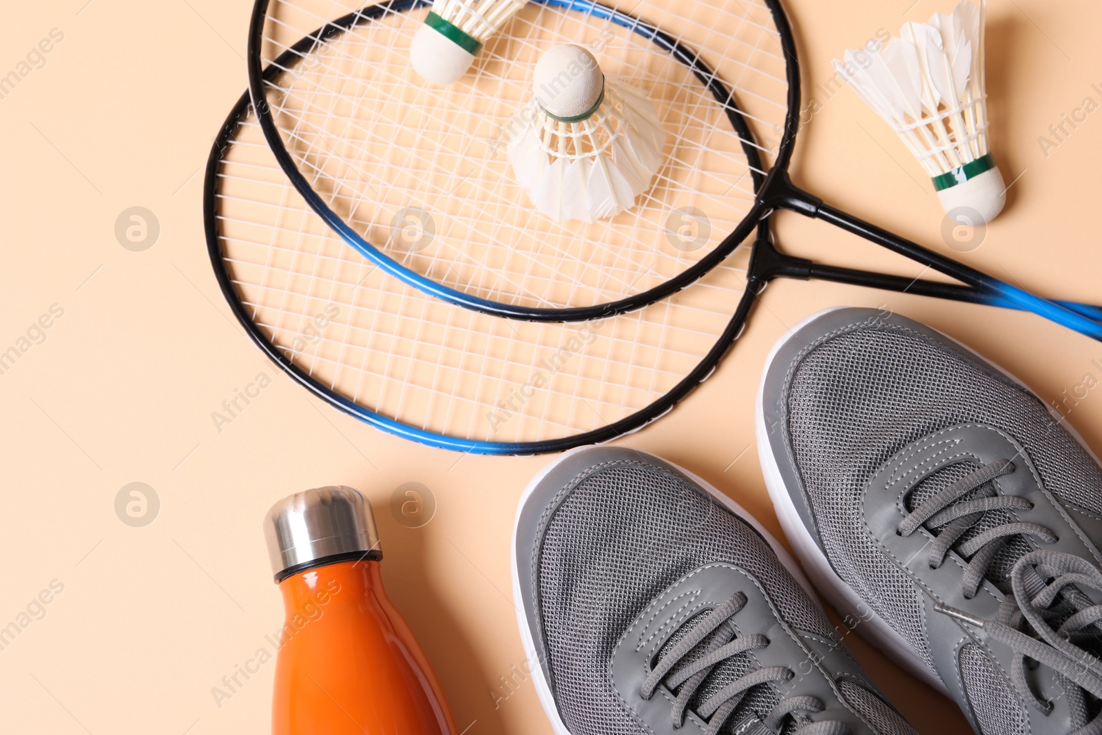 Photo of Feather badminton shuttlecocks, sneakers and bottle on beige background, flat lay