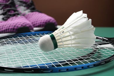 Feather badminton shuttlecock, rackets and sneakers on court, closeup