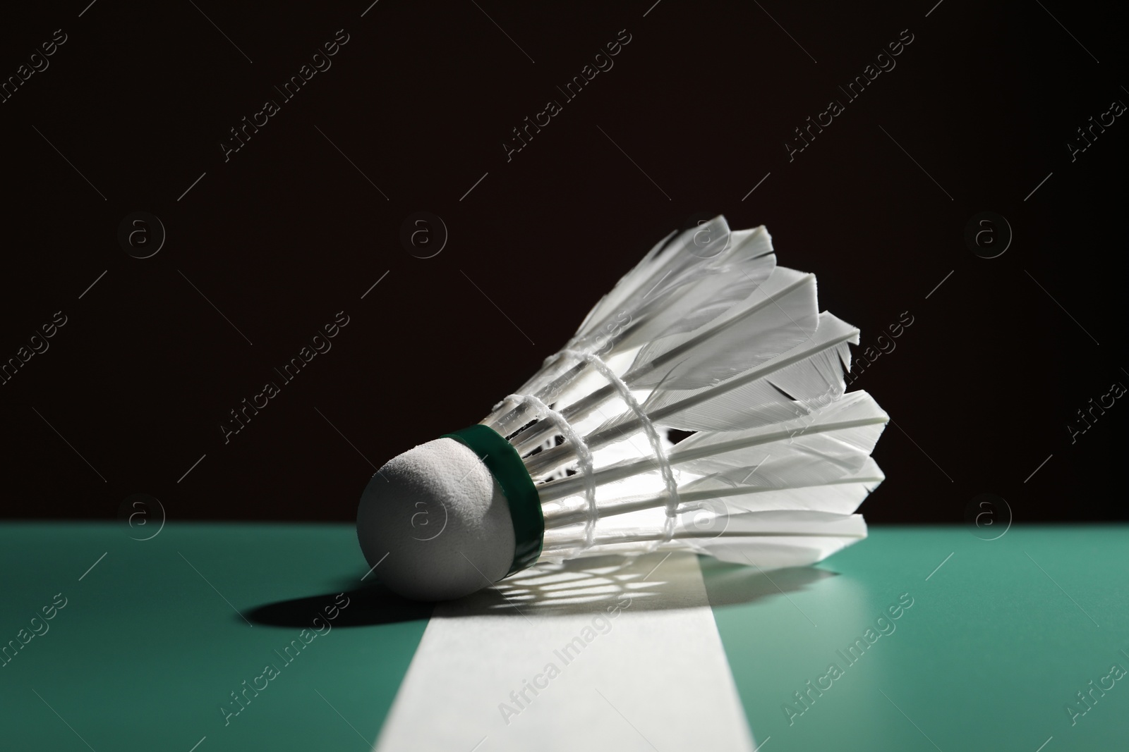 Photo of Feather badminton shuttlecock on green table against dark background