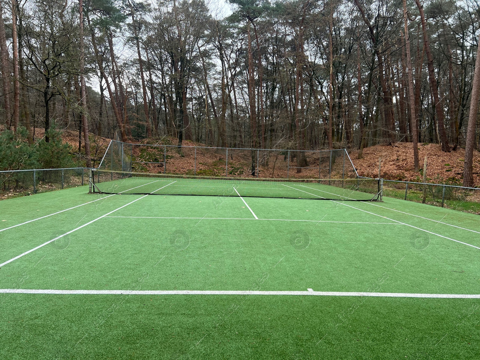 Photo of Tennis court with artificial grass and net outdoors