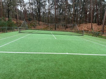 Photo of Tennis court with artificial grass and net outdoors