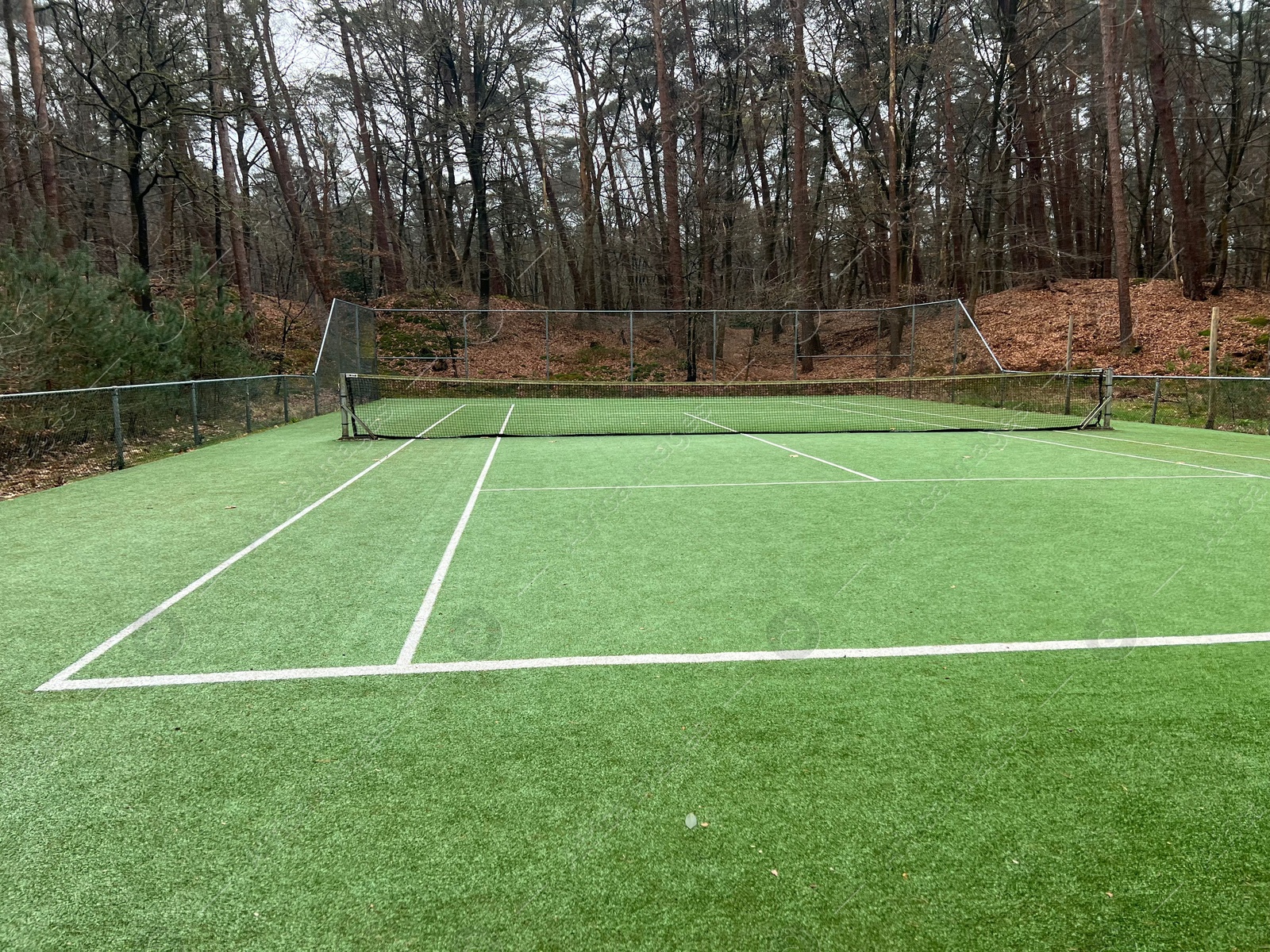 Photo of Tennis court with artificial grass and net outdoors