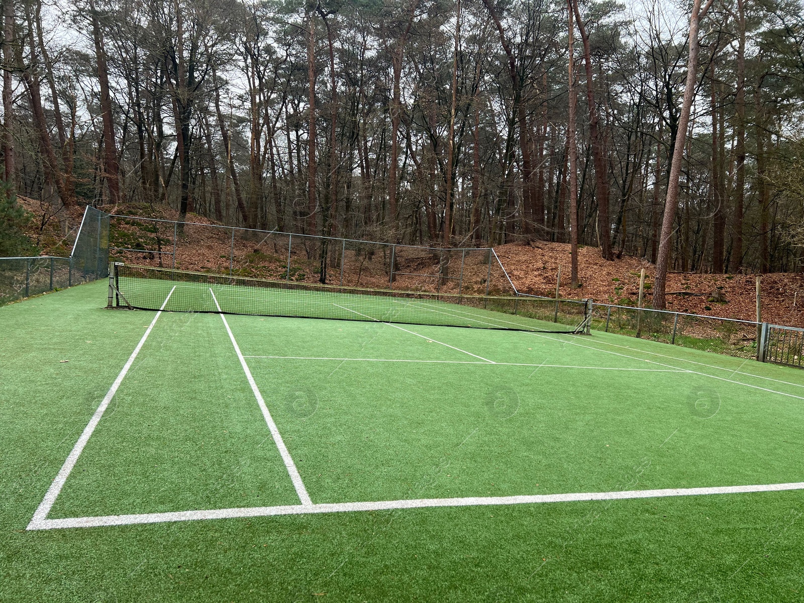 Photo of Tennis court with artificial grass and net outdoors