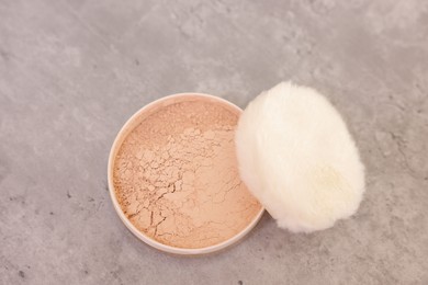 Face powder with puff applicator on grey textured table, top view