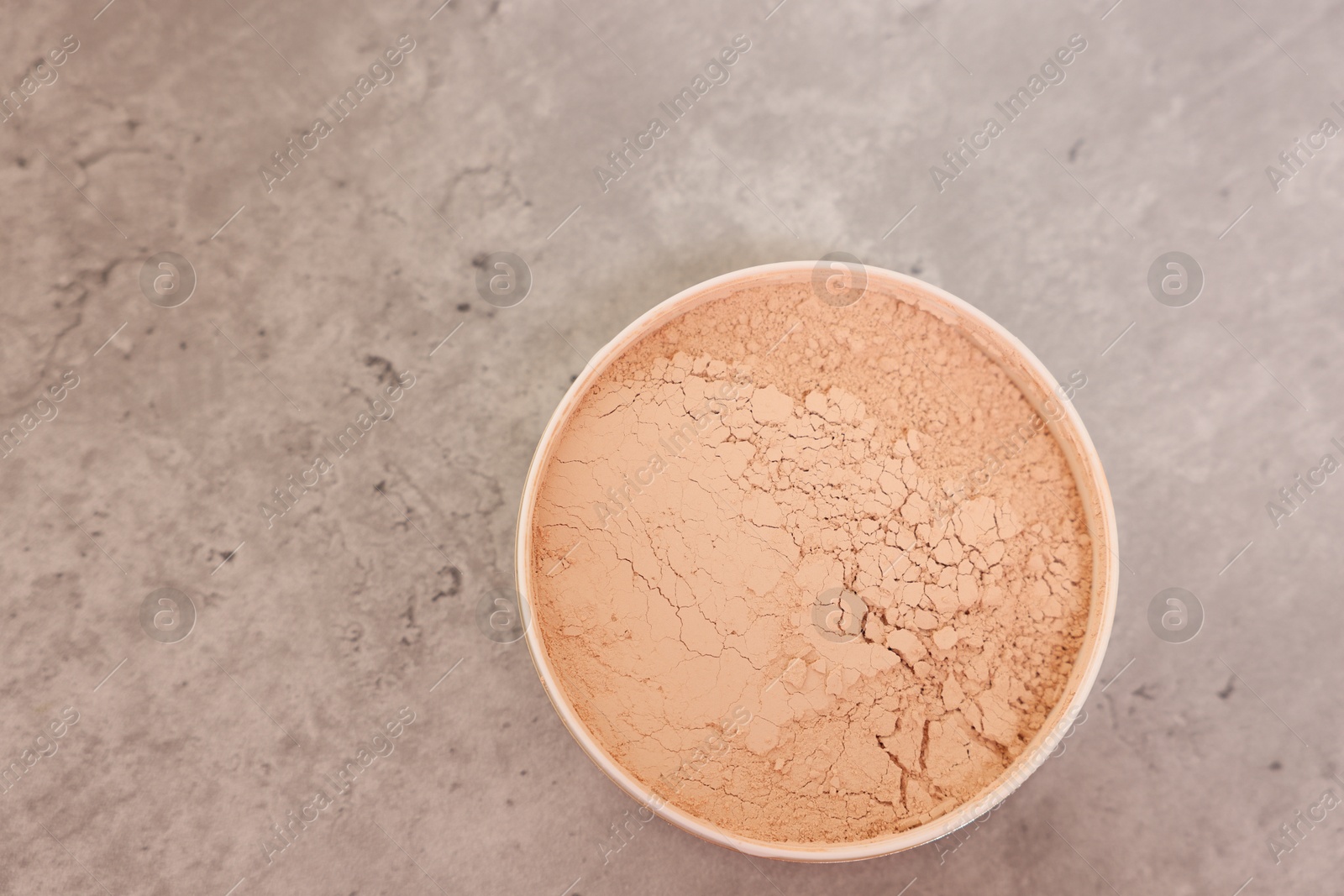 Photo of Face powder on grey textured table, top view. Space for text