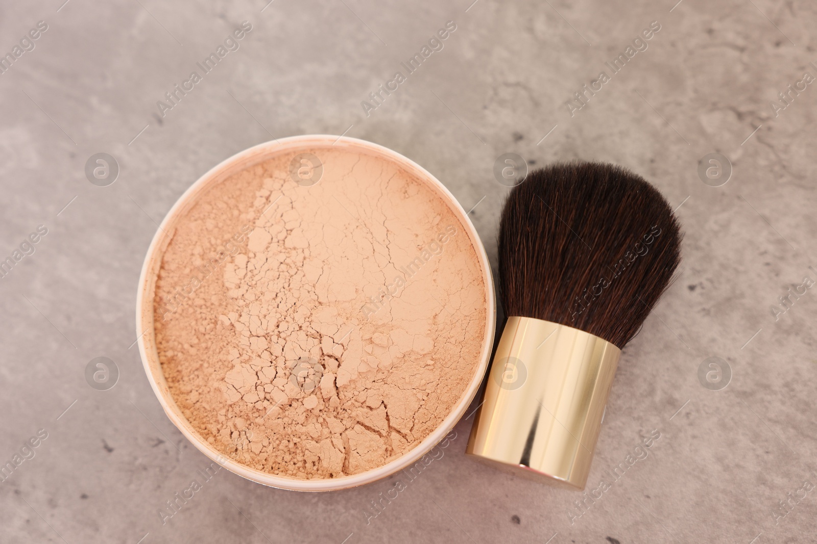 Photo of Face powder and brush on grey textured table, flat lay