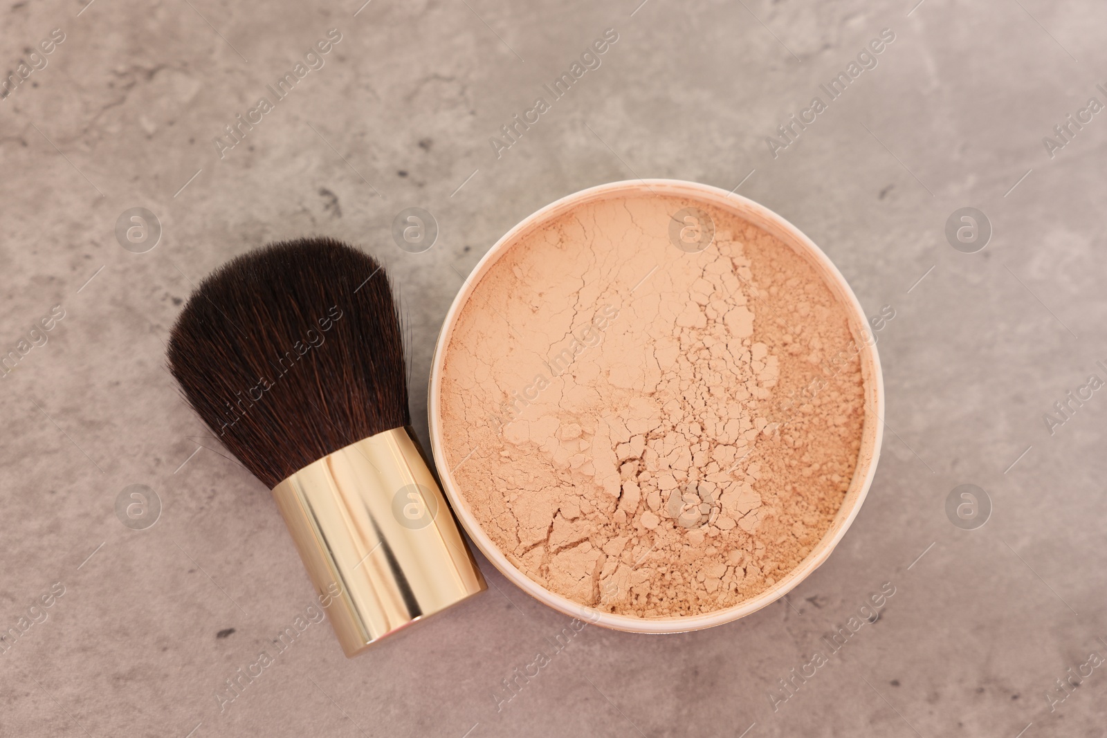 Photo of Face powder and brush on grey textured table, flat lay