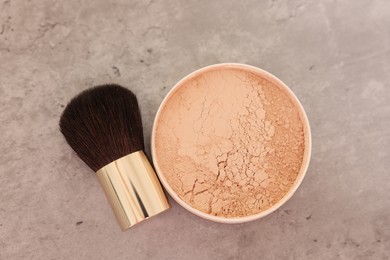 Photo of Face powder and brush on grey textured table, flat lay