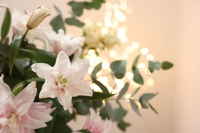 Photo of Bouquet of beautiful lily flowers against beige background with blurred lights, closeup. Space for text