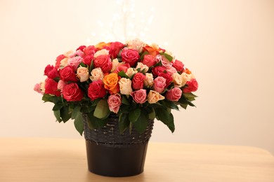Photo of Beautiful bouquet of colorful roses on wooden table
