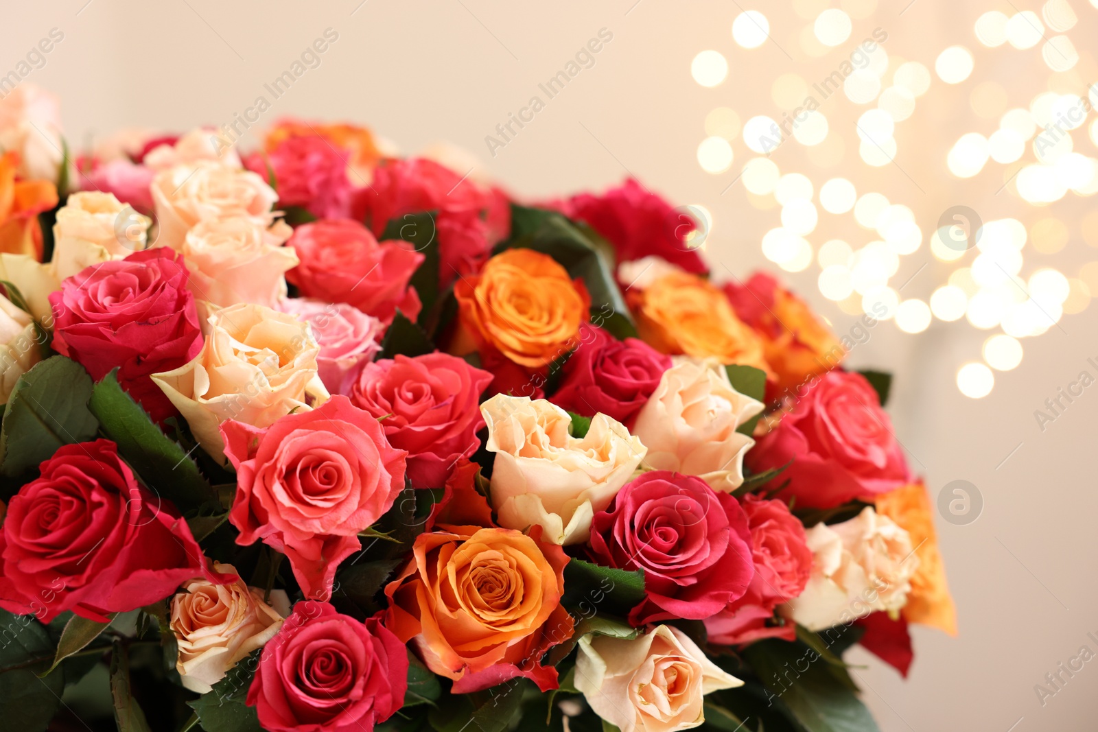 Photo of Beautiful bouquet of colorful roses on beige background, closeup