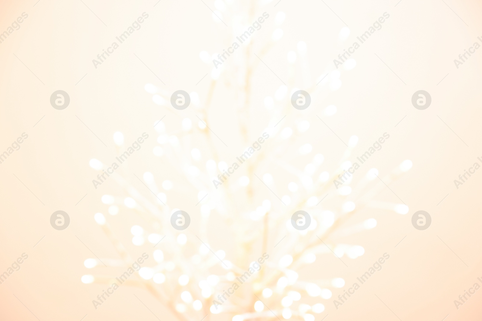 Photo of Decorative tree with lights on beige background, blurred view