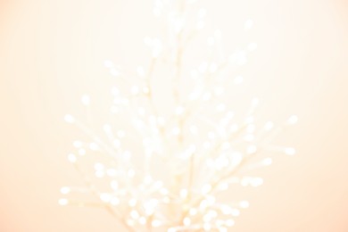 Decorative tree with lights on beige background, blurred view