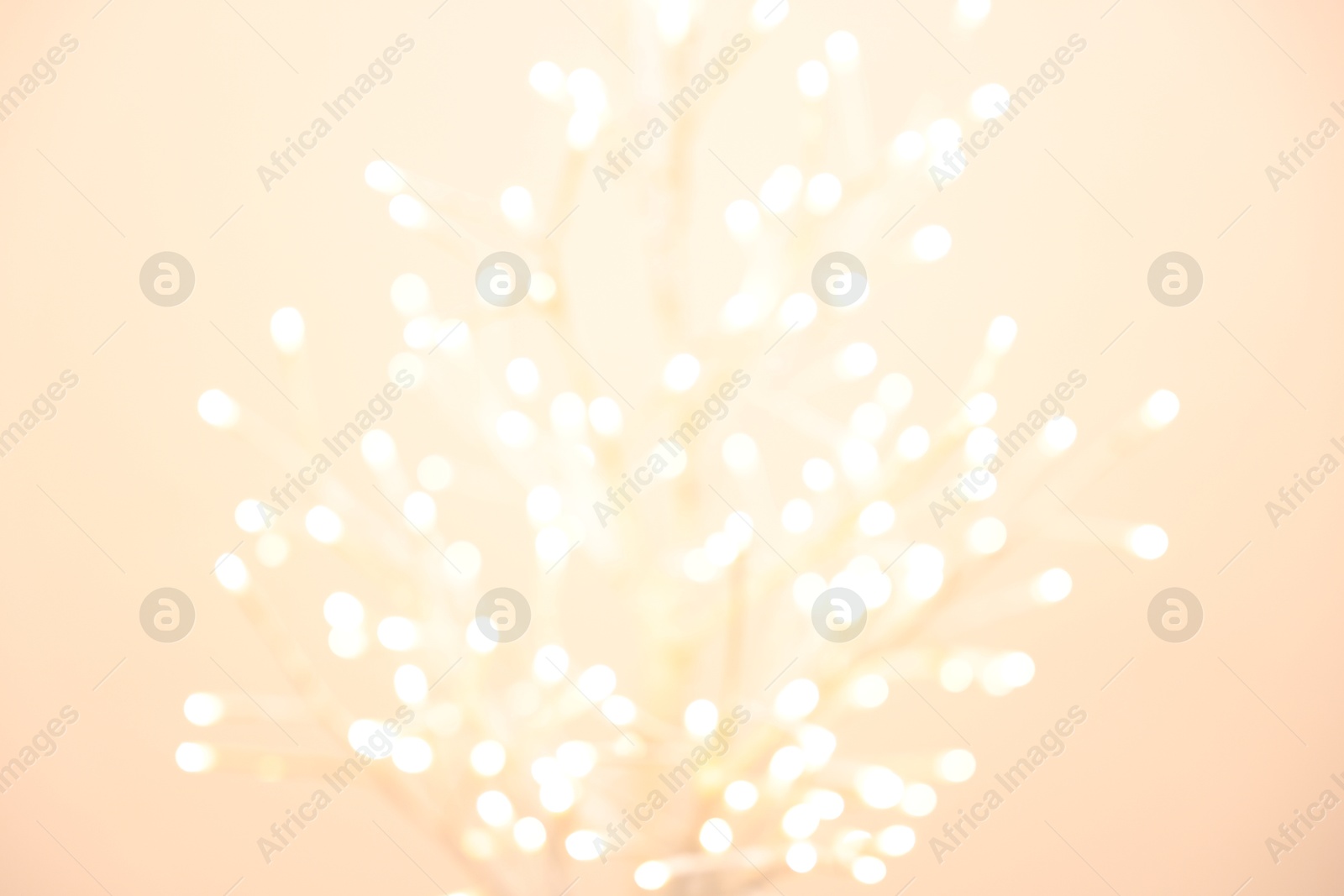 Photo of Decorative tree with lights on beige background, blurred view