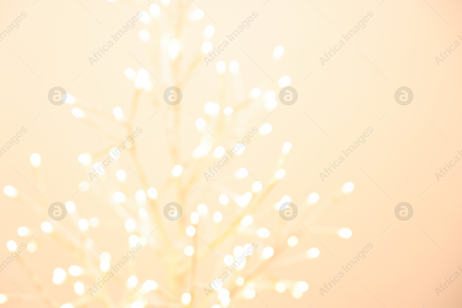 Photo of Decorative tree with lights on beige background, blurred view