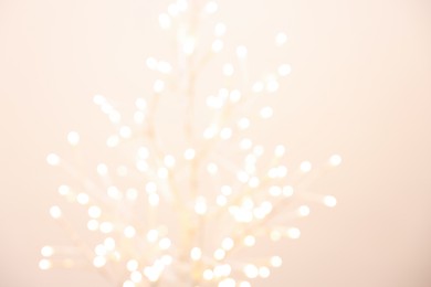 Decorative tree with lights on beige background, blurred view