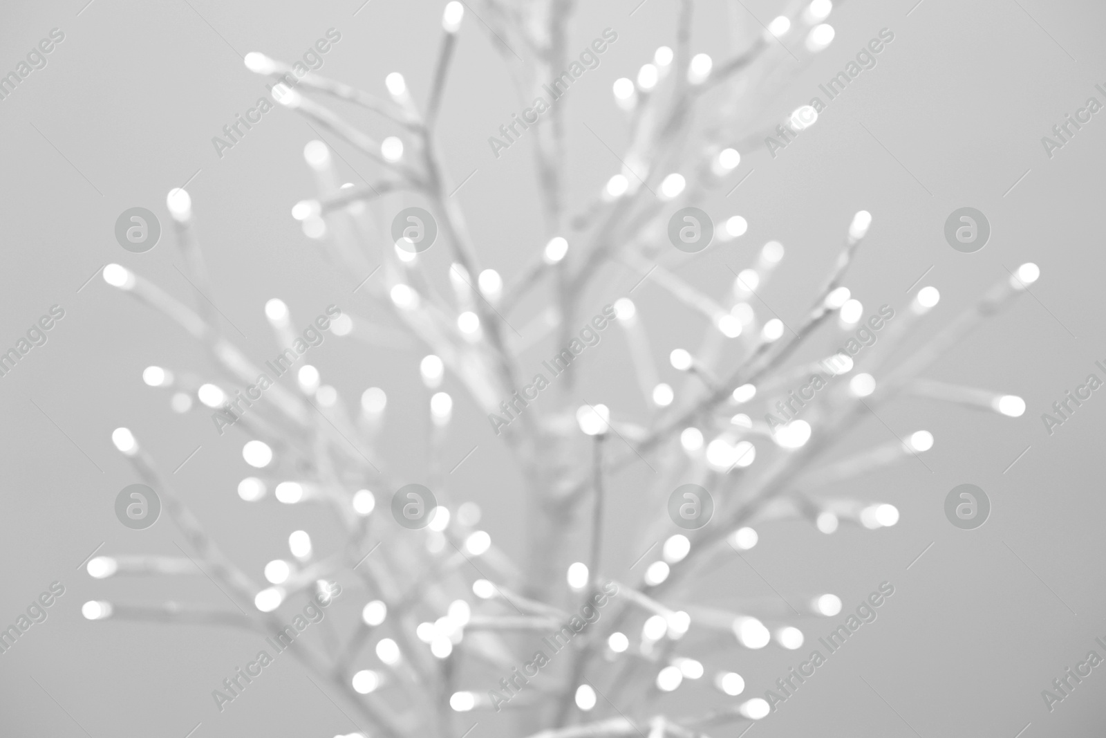 Photo of Decorative tree with lights on beige background, blurred view