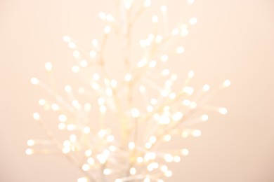 Decorative tree with lights on beige background, blurred view