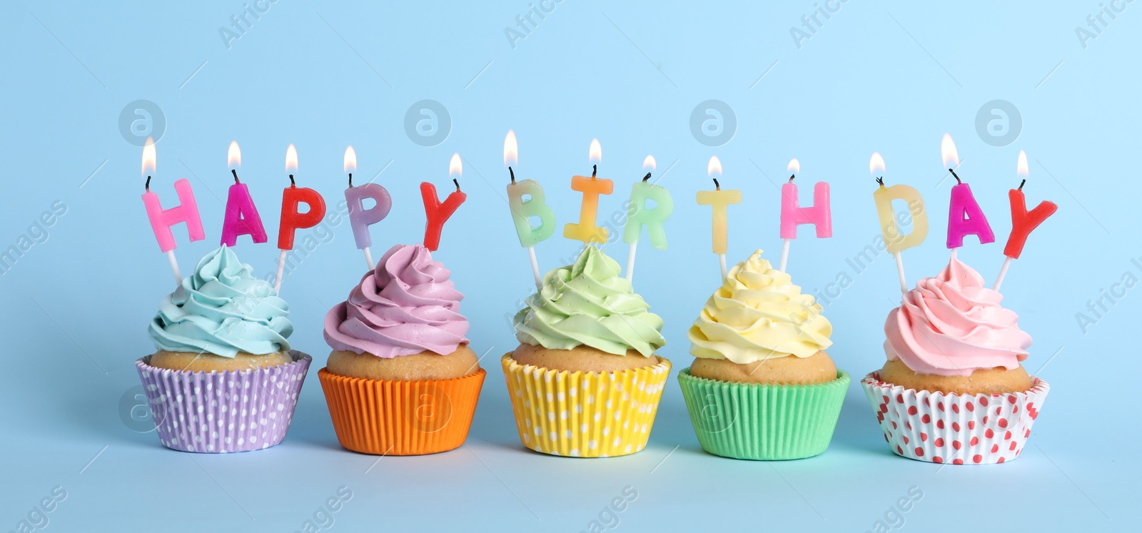 Photo of Birthday cupcakes with burning candles on light blue background