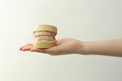 Photo of Woman holding dental model with jaws on white background, closeup. Cast of teeth