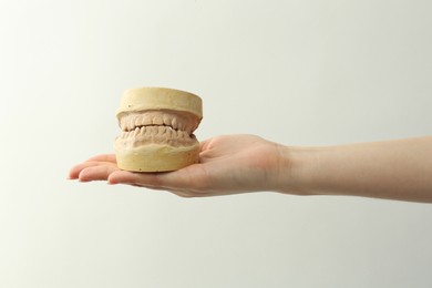 Woman holding dental model with jaws on white background, closeup. Cast of teeth