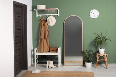 Image of Stylish hallway with shoe storage bench and mirror near sage green wall. Interior design