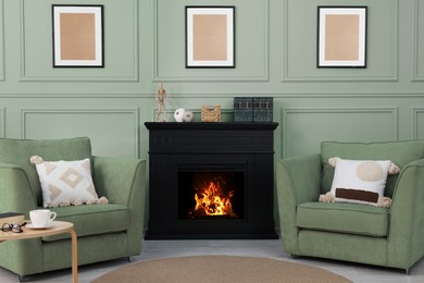 Image of Stylish fireplace and armchairs near sage green wall indoors. Interior design