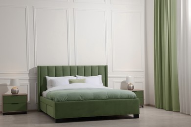 Image of Comfortable sage green bed in room. Interior design